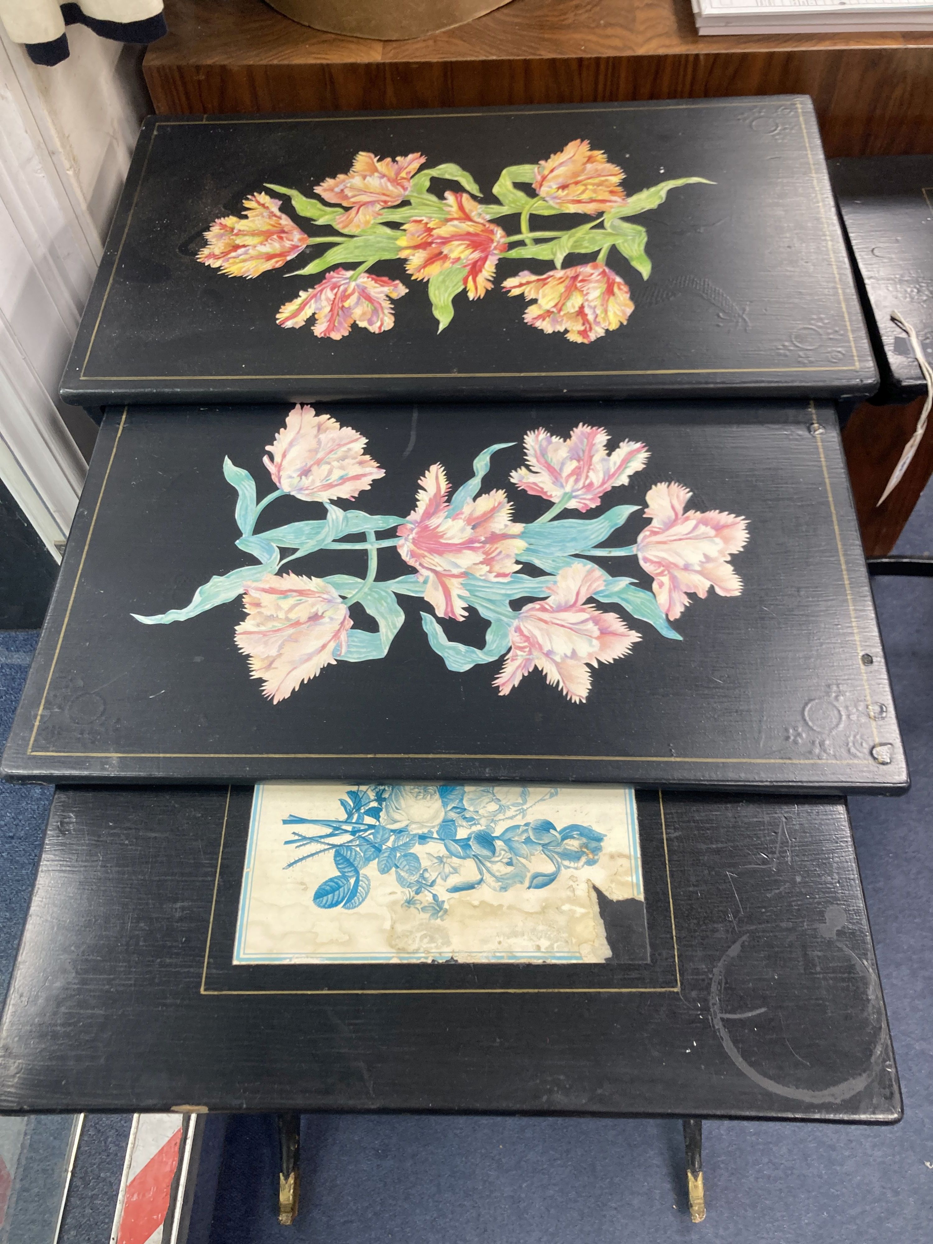 A graduating nest of four Regency style occasional tables with lyre shaped supports, black painted finish with gilt mask detail to supp